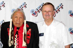 A man and an older native american standing next to each other.